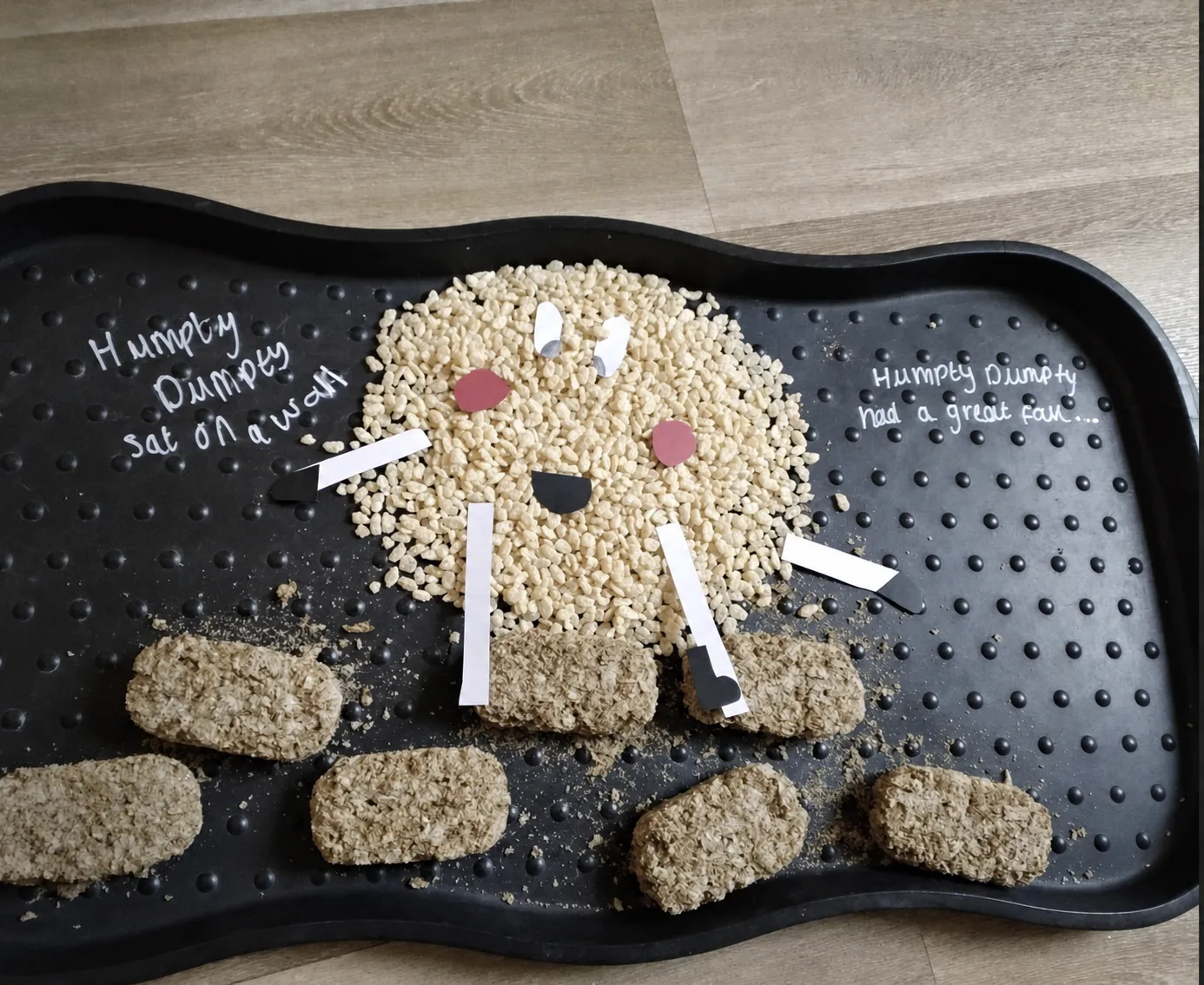 A Humpty Dumpty themed cereal sensory tray with a wall and character shape