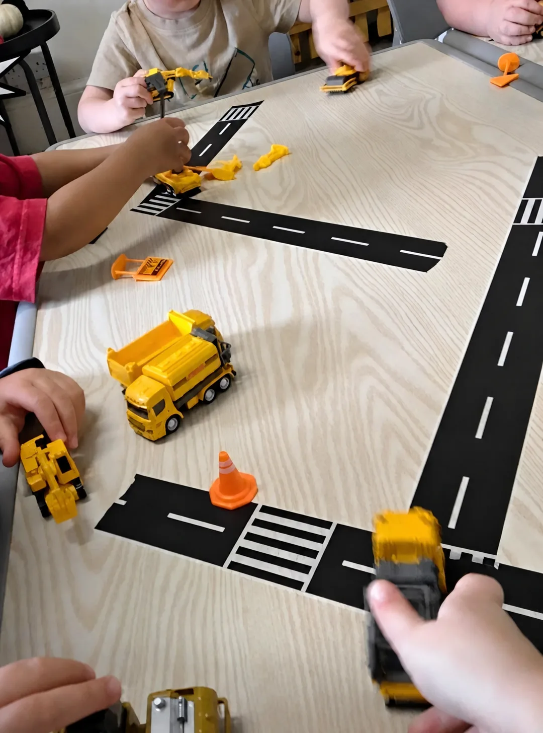 Toy construction vehicles and cones on a road layout used for small-world play
